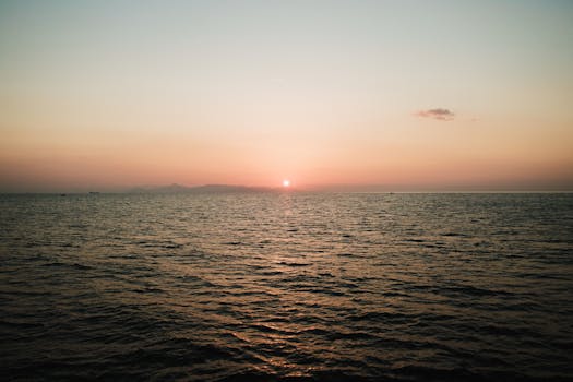 A calming sunset over a vast ocean with gentle waves creating a peaceful atmosphere.