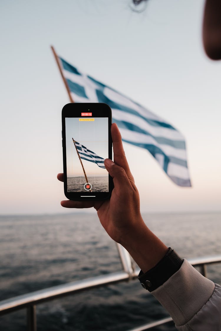 Man Hand Holding Smartphone And Recording Flag Of Greece