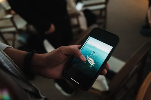 A person holding a cell phone with a photo of a boat