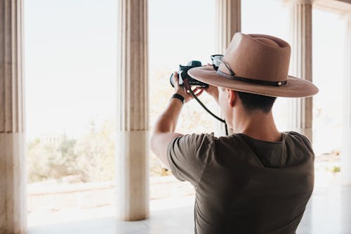 Man in Hat Taking Pictures of Columns