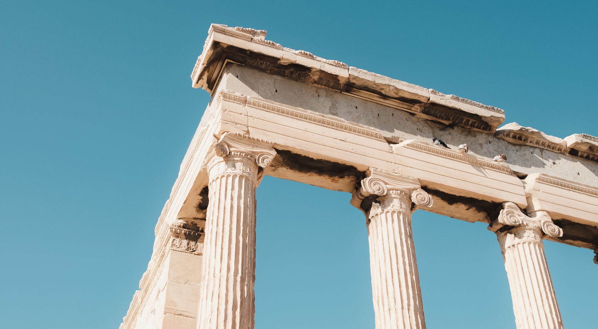 Weathered marble columns of an ancient Greek temple against the sky