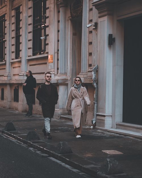 Free Stylish individuals walking on an urban street, showcasing modern city fashion in a moody atmosphere. Stock Photo