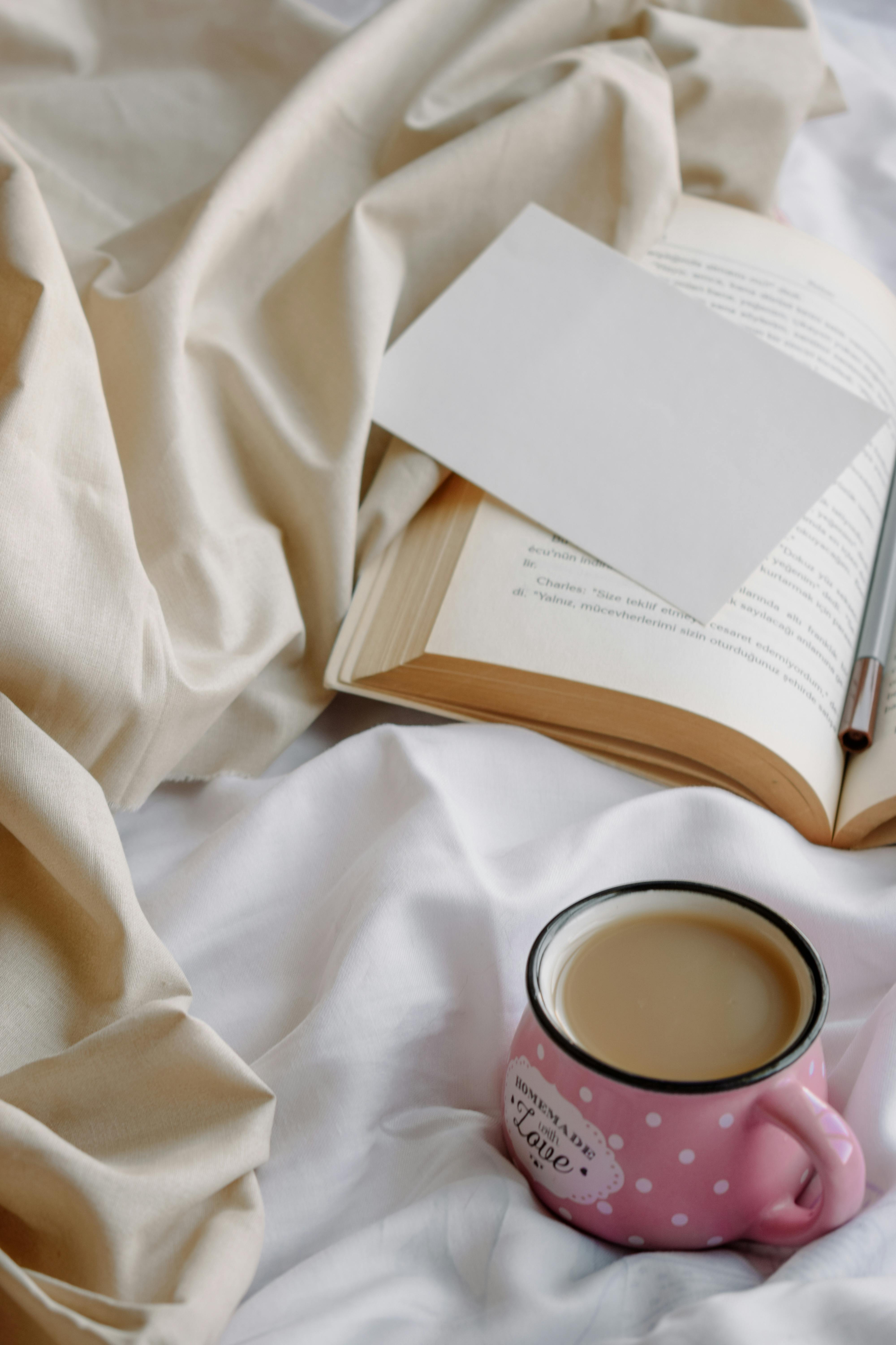 a cup of coffee and a book on a bed