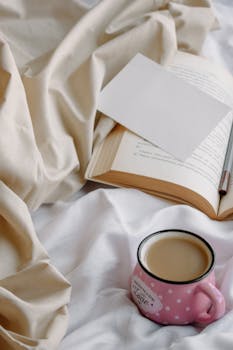 Relaxing morning setup with coffee and open book on bed.