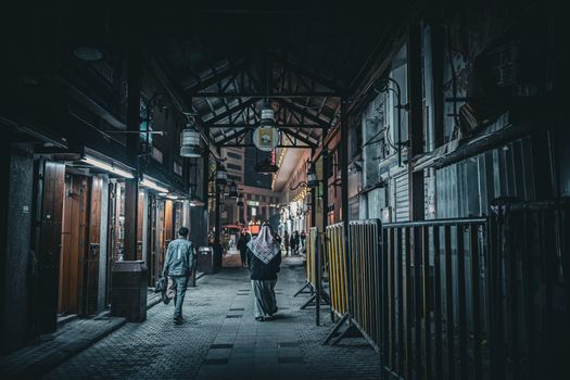 Urban night scene in Kuwait City with people walking through Al Mubarakiya, illustrating vibrant local culture.