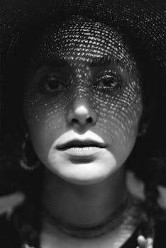 Black and white portrait of a woman with dramatic shadows from a hat.