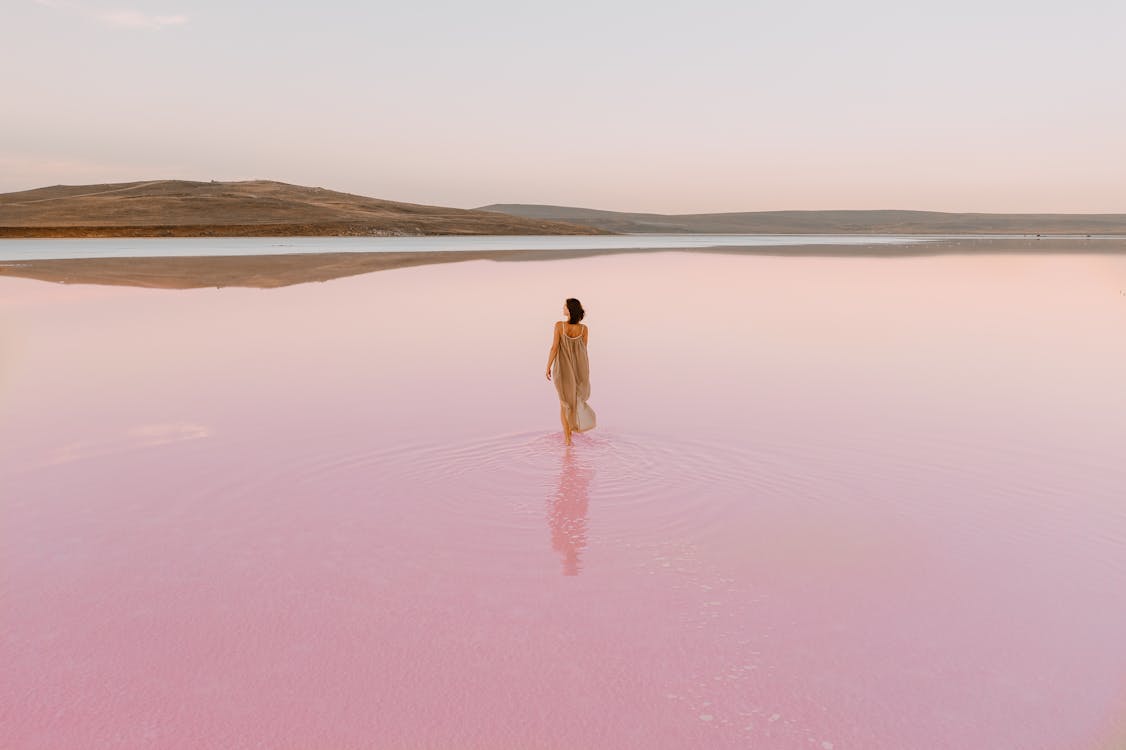 Woman Walking in Pink Water of a Lake