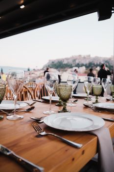 Sophisticated outdoor dining setup with glassware and cutlery overlooking a cityscape.