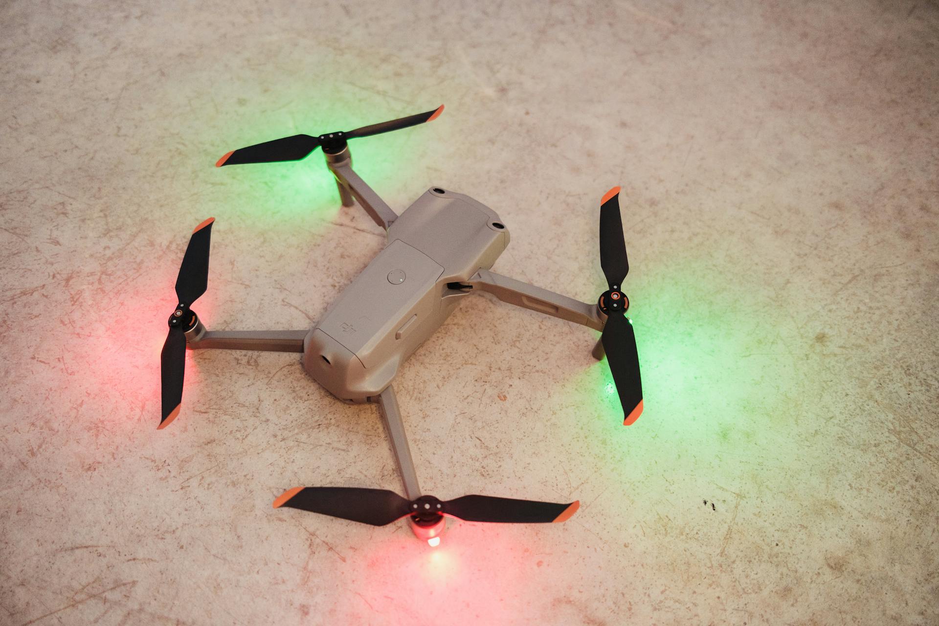 Overhead view of a modern drone with LED lights on a textured surface.