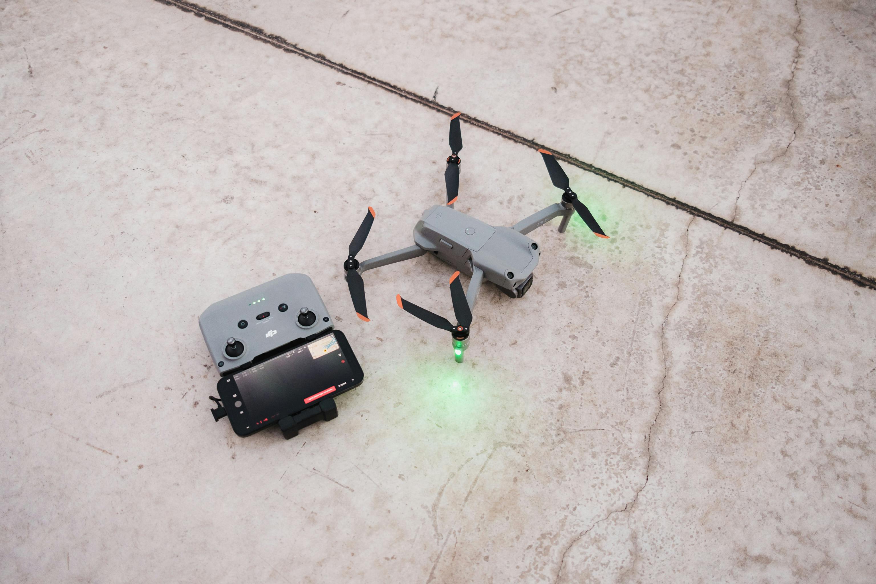 Free A close-up overhead view of a drone and controller on a concrete surface, showcasing technology. Stock Photo