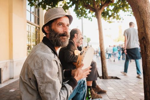 Free Portrait of a street musician playing tambourine on a lively urban street. Stock Photo