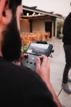 Close-up of a man with a beard holding a drone controller outdoors, focusing on the screen display.