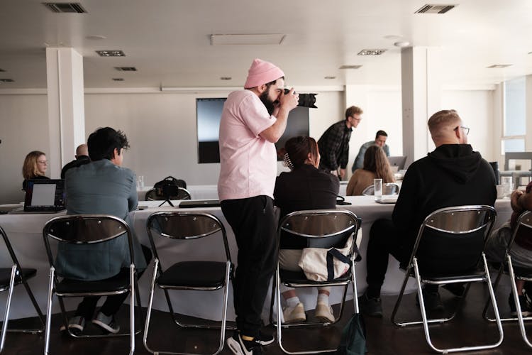 A Man Taking A Picture Of People In A Room