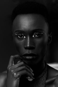A captivating black and white close-up portrait of a woman with creative makeup and a thoughtful expression.