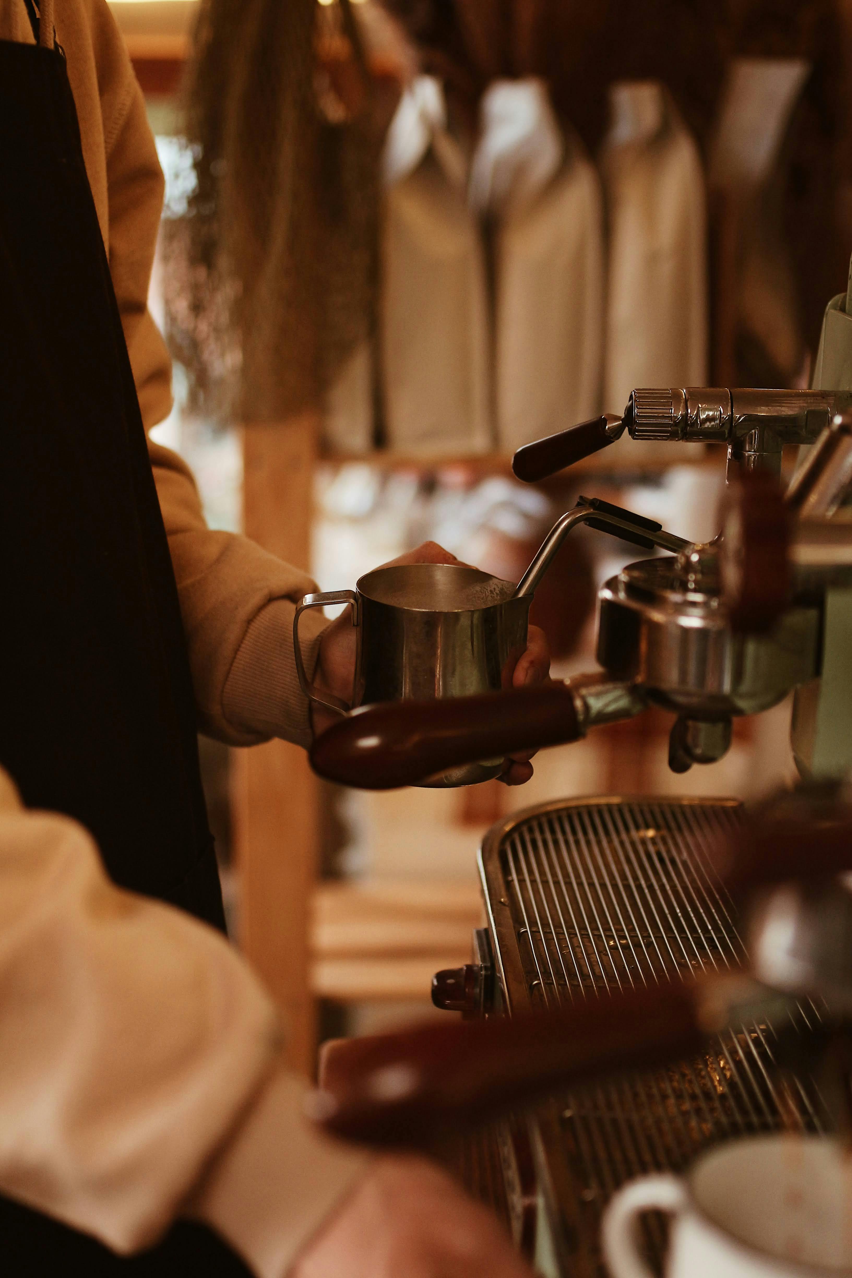A barista expertly uses an espresso machine to prepare a hot beverage in a cozy cafe atmosphere.