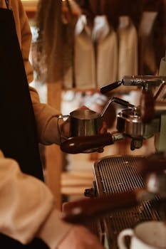 A barista expertly uses an espresso machine to prepare a hot beverage in a cozy cafe atmosphere.