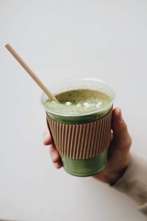Photo of a Person's Hand Holding a Cup with Matcha Latte