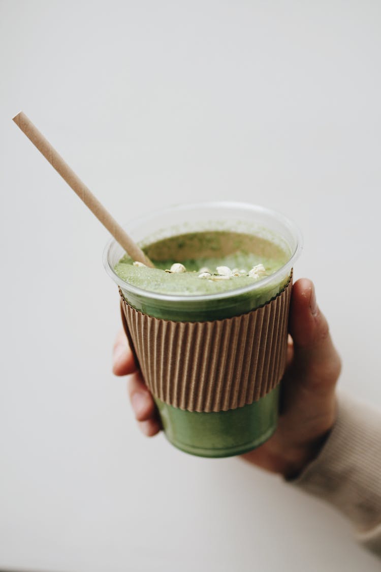 Photo Of A Person's Hand Holding A Cup With Matcha Latte