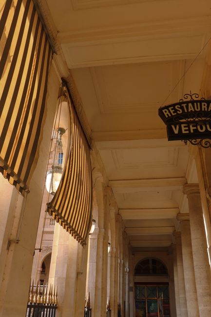 Stylish hallway in Paris featuring classic architecture, striped canopies, and columned design.