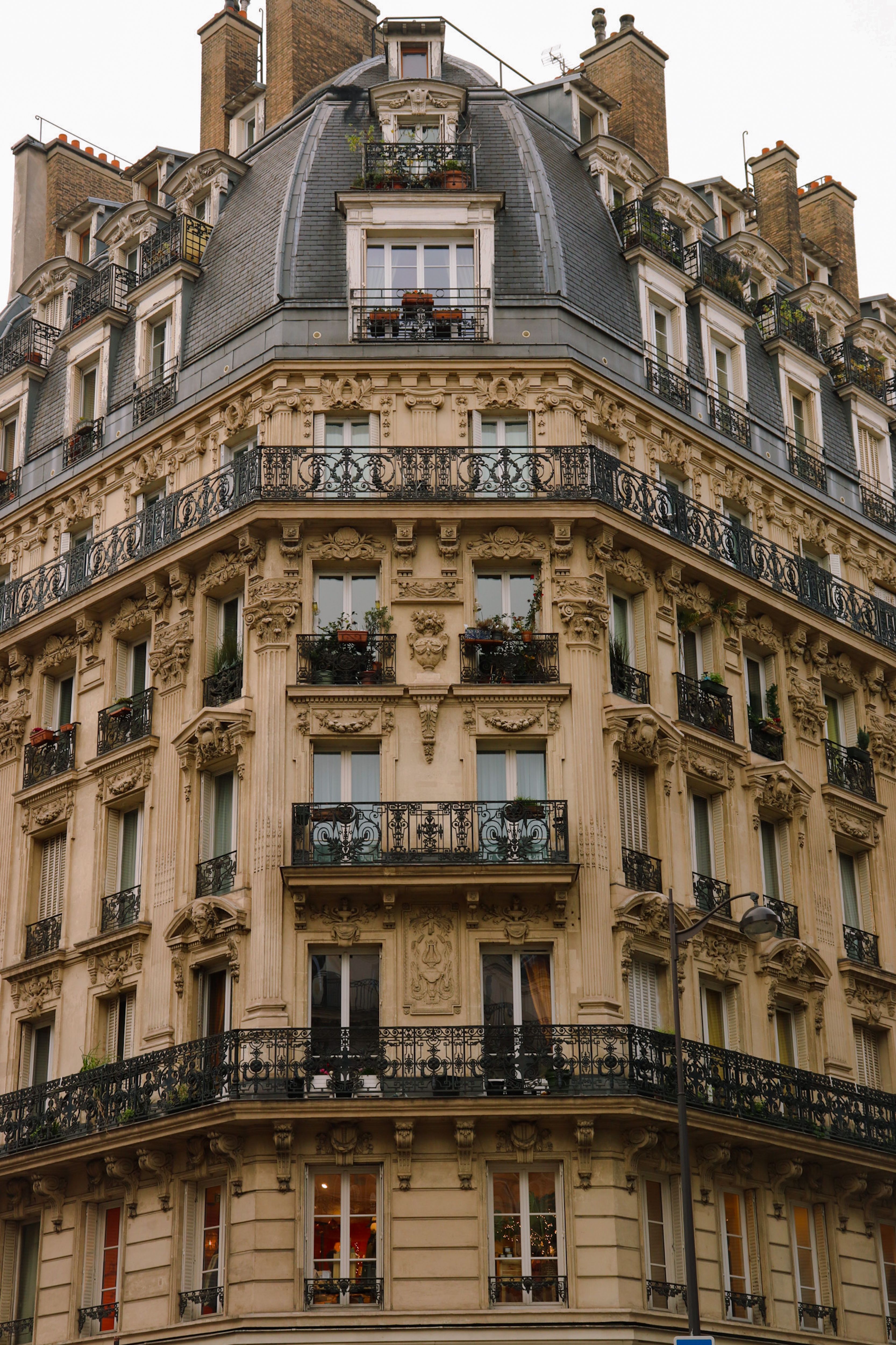 Façade haussmannienne aux balcons superposés, dans un quartier dense.