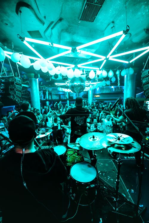 Free Dynamic live concert scene with drummers on stage, vibrant blue lighting, and a lively crowd. Stock Photo
