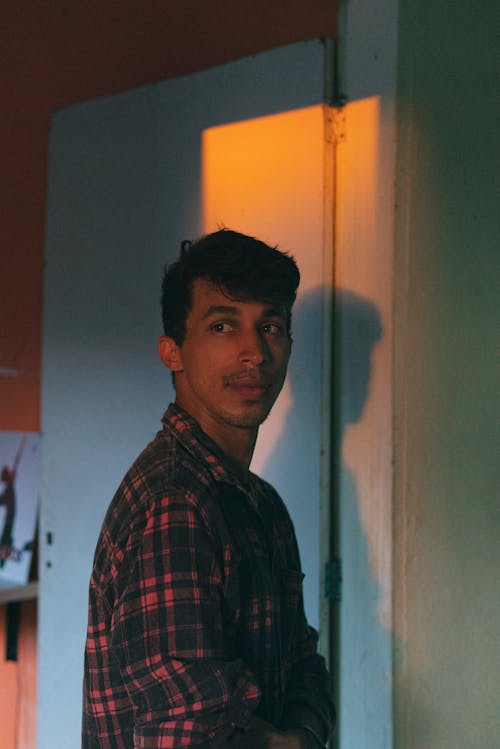 Young Man in a Checkered Shirt Standing in the Door 
