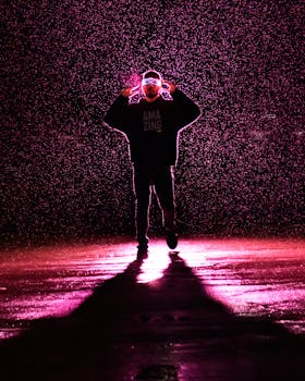 Silhouette of a person posing under pink light in the rain, creating a dramatic visual.