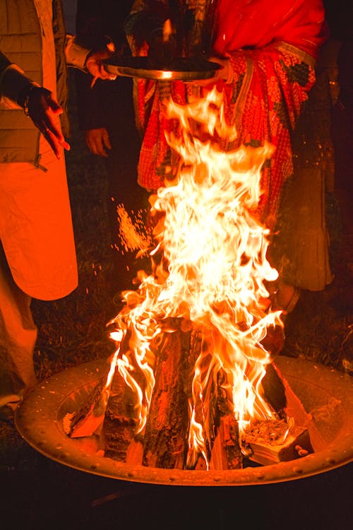 People in Traditional Clothing Standing by the Fire 