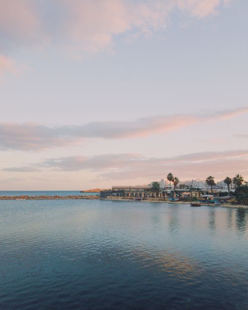 Free Explore the tranquil beauty of Monastir's coast at sunset with calm seas and palm-lined resorts. Stock Photo
