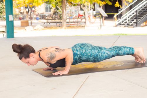 Free Female athlete in plank pose performing yoga outdoors on a sunny day. Stock Photo