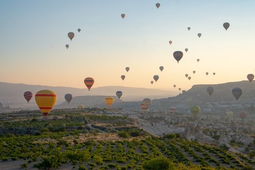 Stunning view of hot air balloons flying above Cappadocia's landscape at sunrise.