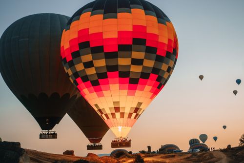 Free Vibrant hot air balloons soaring over Cappadocia at sunset, capturing a serene travel experience. Stock Photo