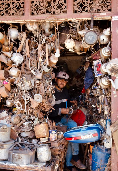 Free A craftsman surrounded by antique items in a busy workshop, showcasing traditional pottery skills. Stock Photo