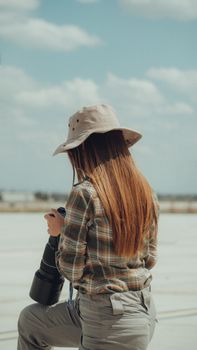 Back view of a woman outdoors holding a camera, showcasing photographer lifestyle.