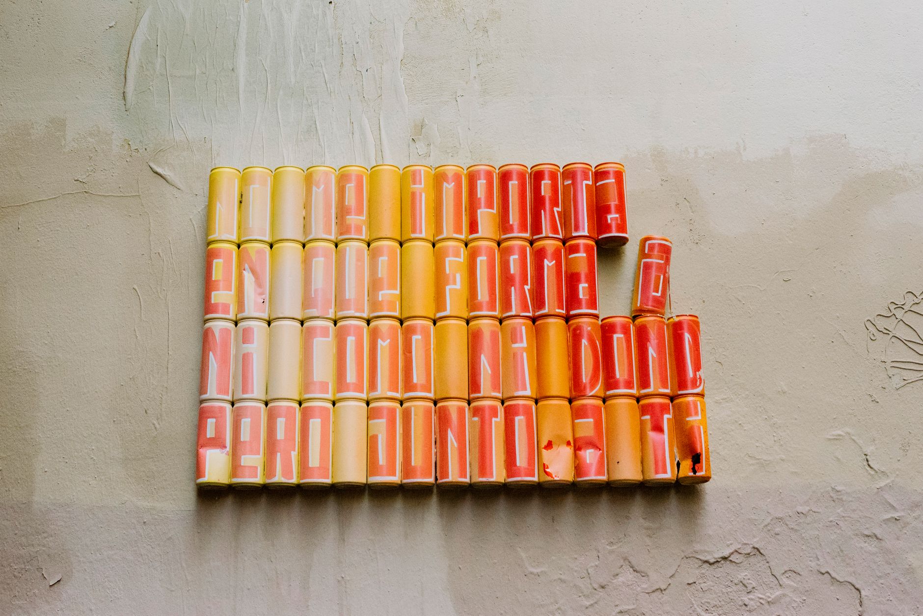 Creative art installation with colored soda cans forming text on a wall.