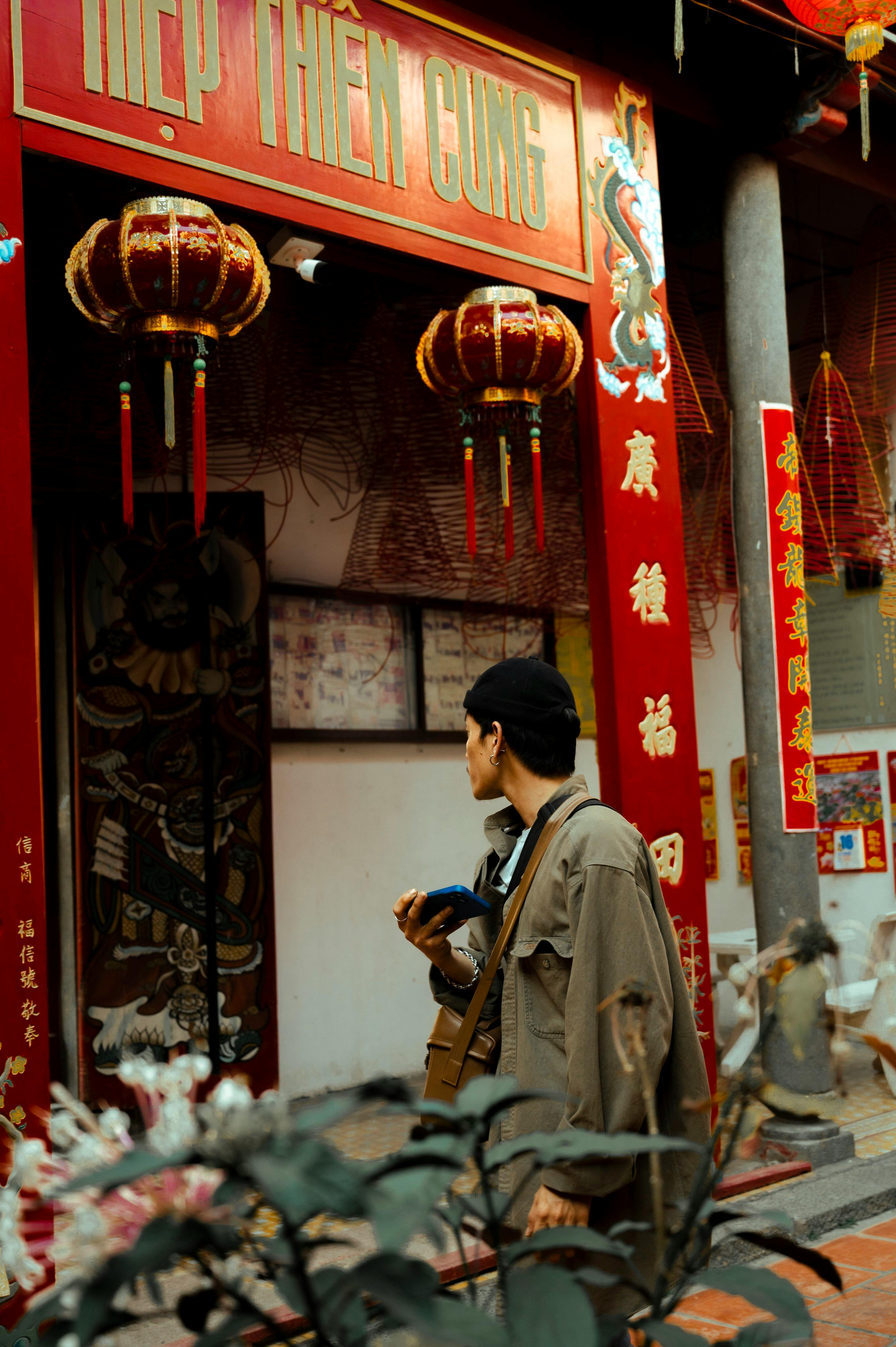 A man inspects traditional decorations at a vibrant temple entrance in Can Tho, Vietnam.