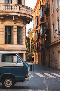 A picturesque street in Spain featuring a vintage van and historic architecture at sunset.