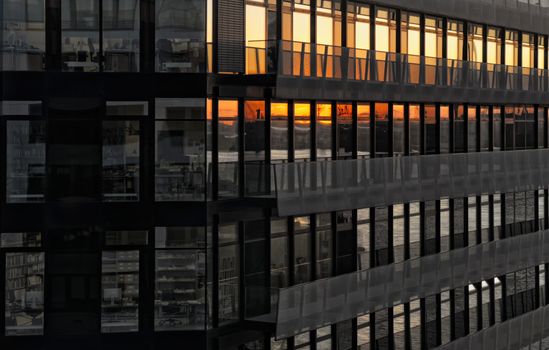 Urban building facade reflecting a beautiful sunset in the windows.