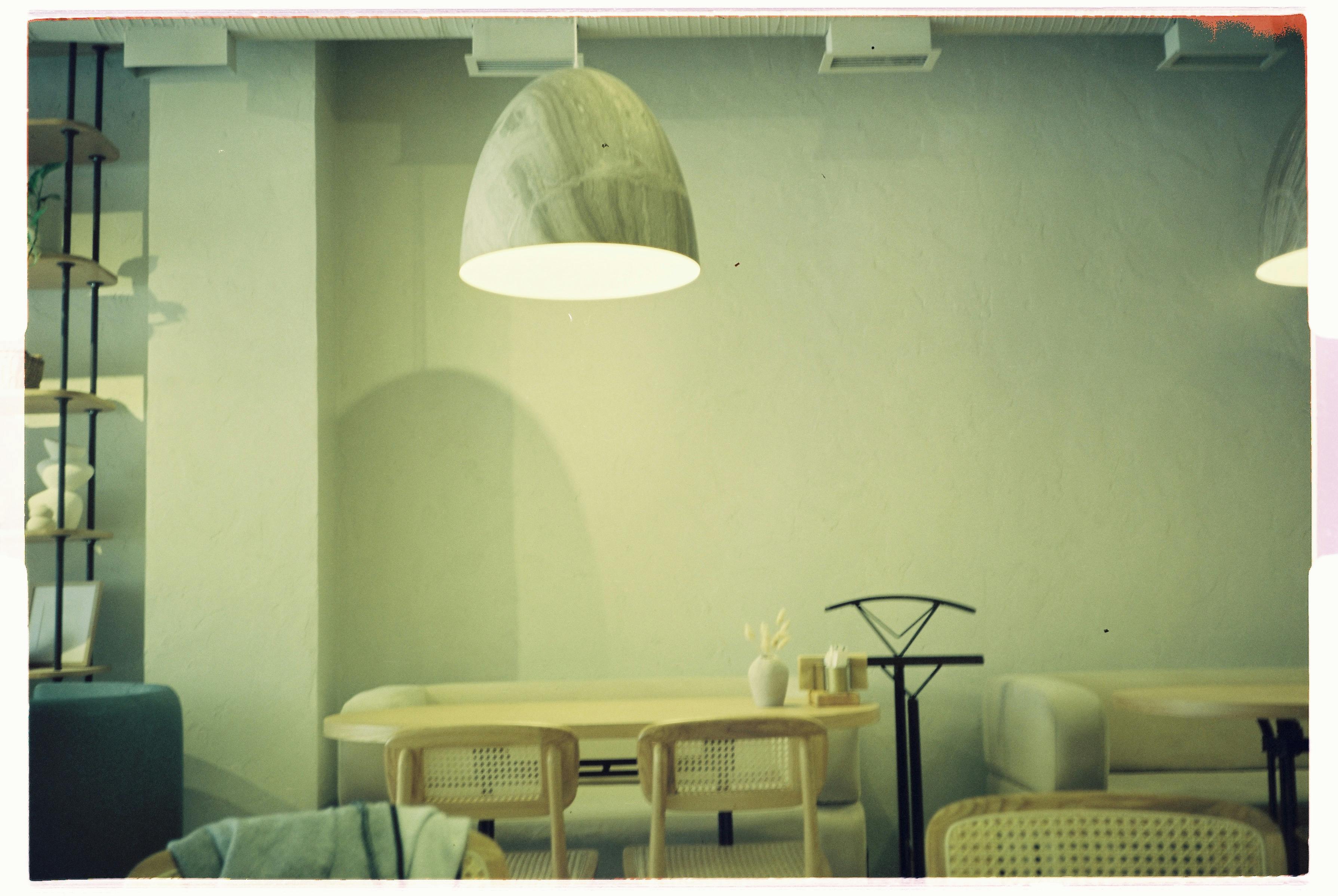 A modern cozy living room featuring a stylish table, chairs, and hanging lamp.