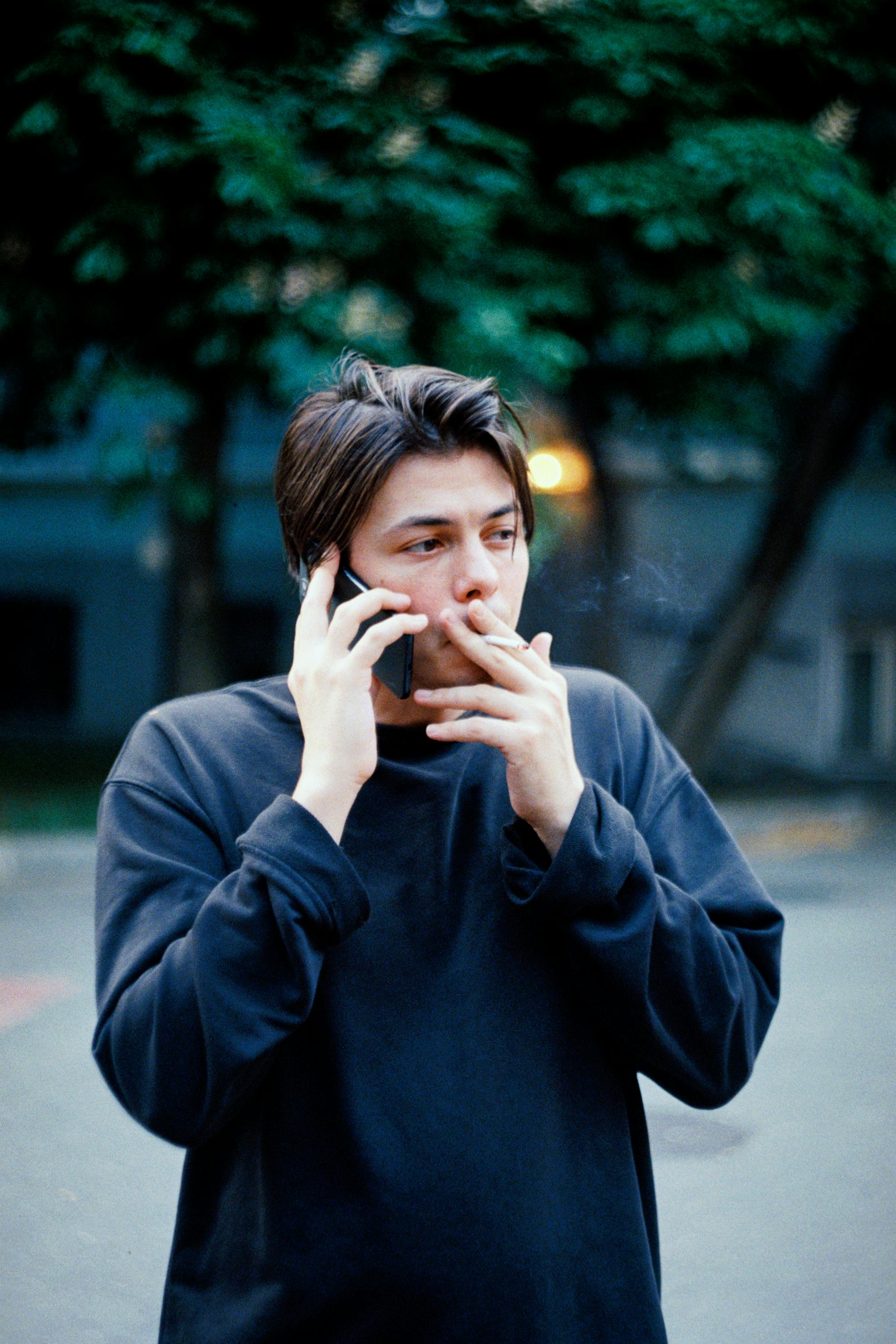 man talking on the phone and smoking a cigarette