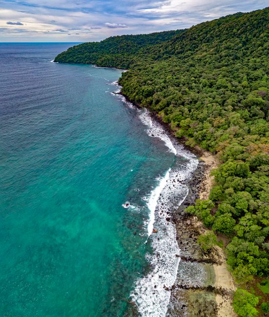 Stunning aerial view of a tranquil beach and lush forest coastline in Sukakarya, Aceh, Indonesia.