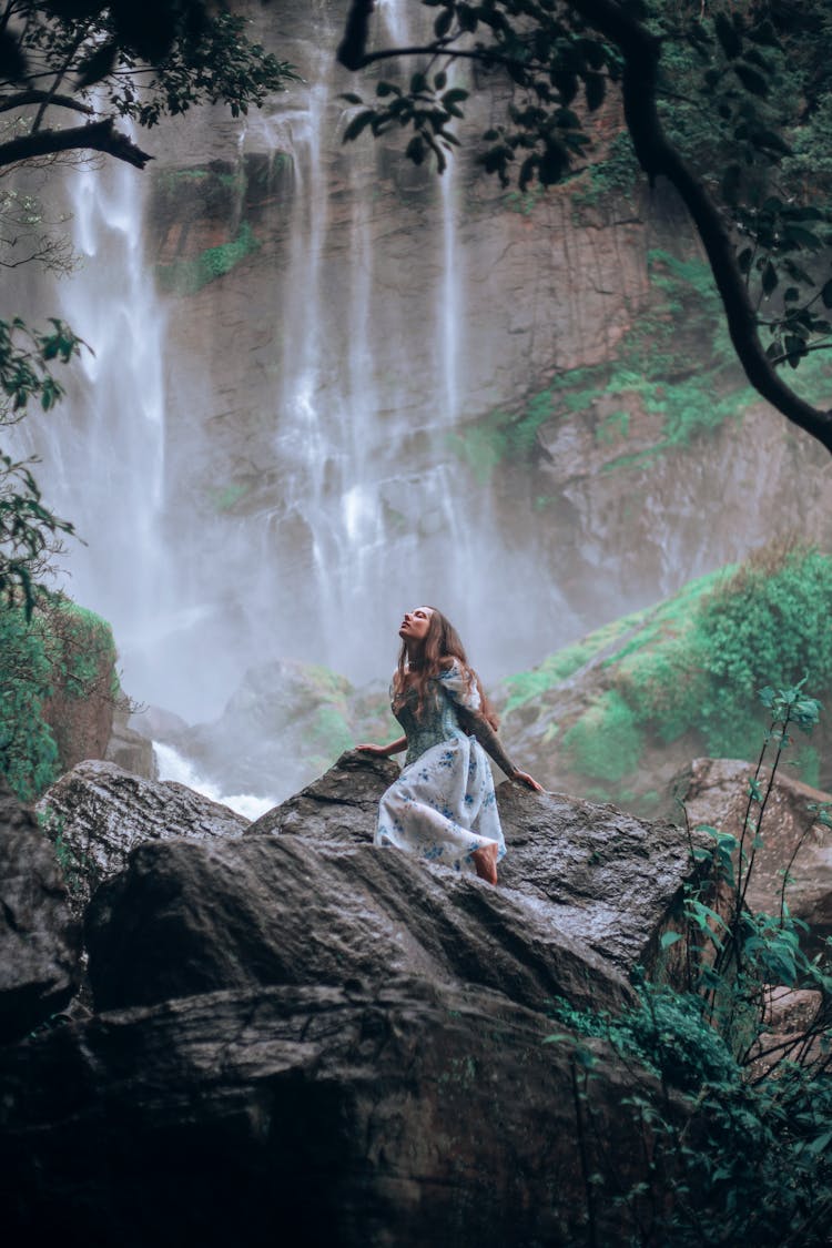 Woman Standing On A Rock Under A Waterfall 