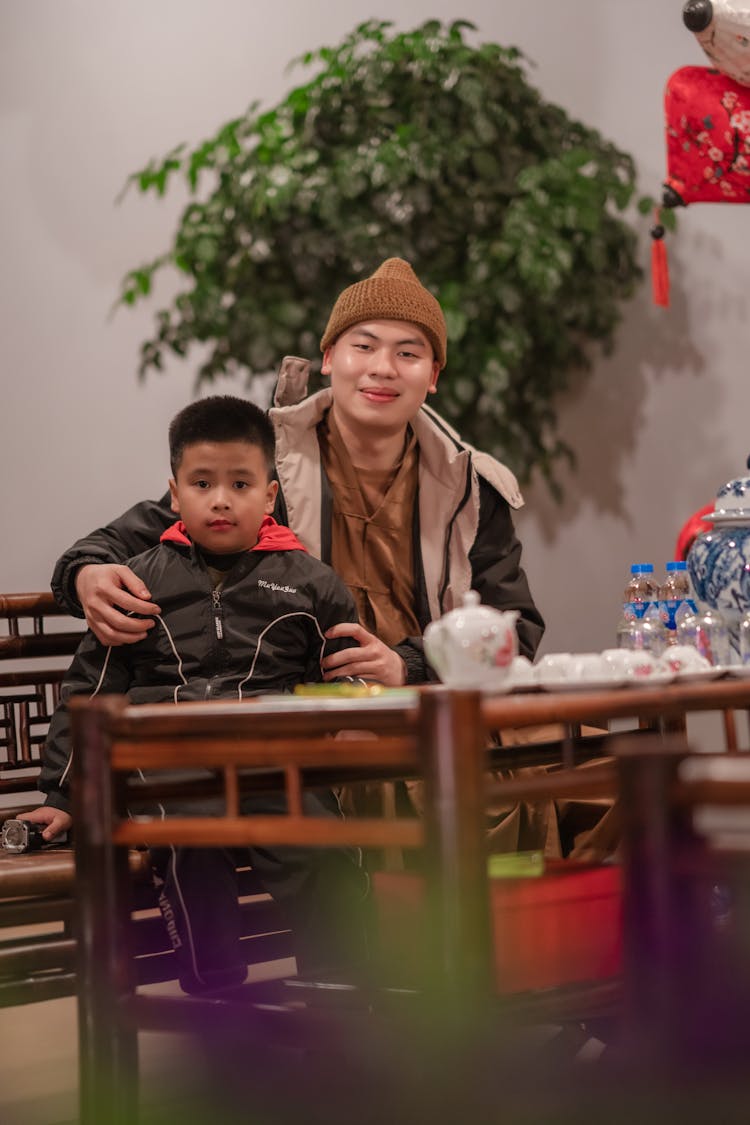 A Man And A Young Boy Sitting On Wooden Bench