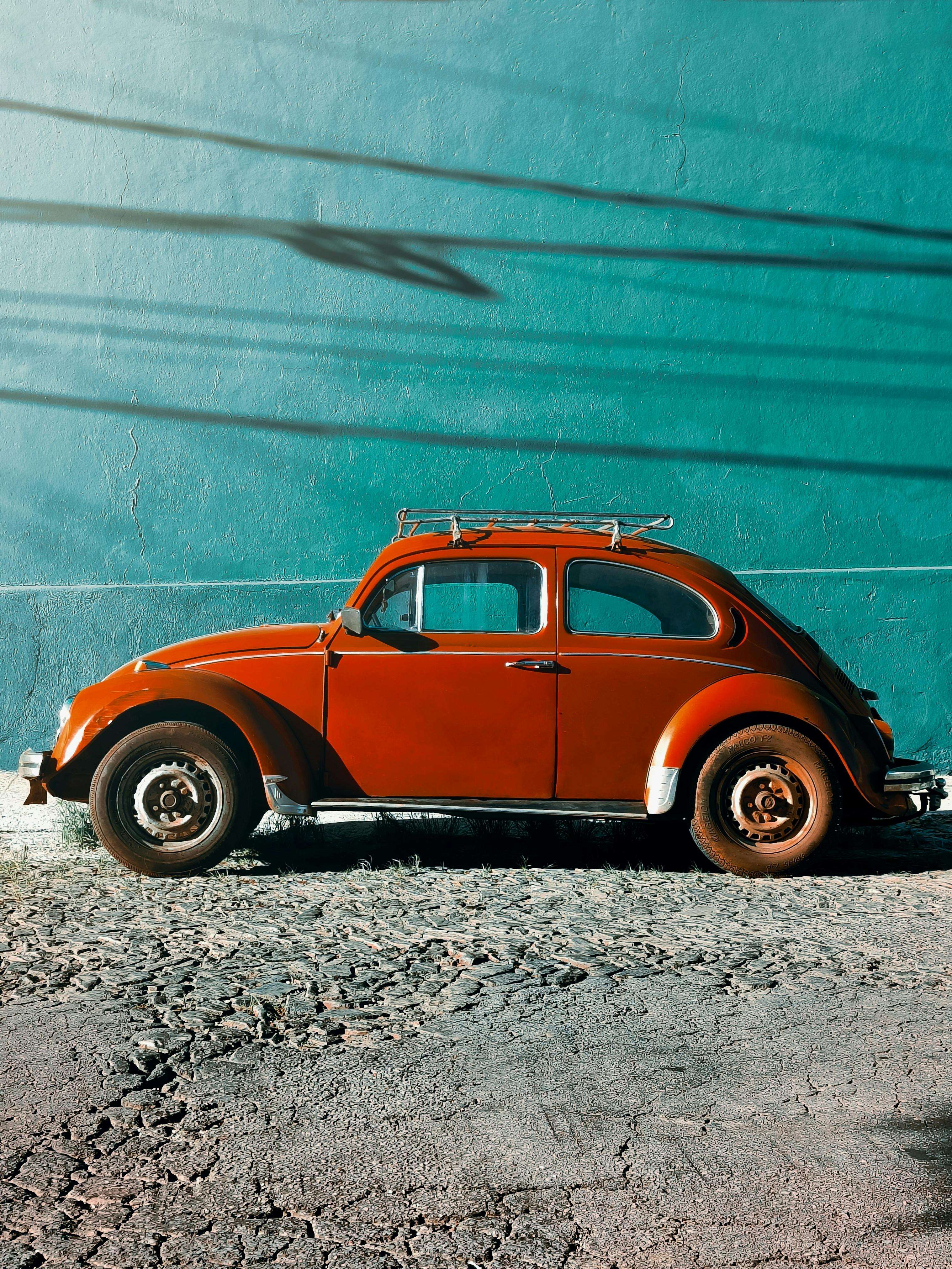 Red Volkswagen Beetle Parked Near Green Wall · Free Stock Photo