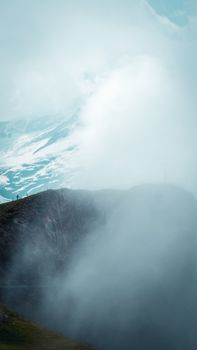 Ethereal mountain landscape shrouded in mist and dramatic clouds, creating a serene natural scene.
