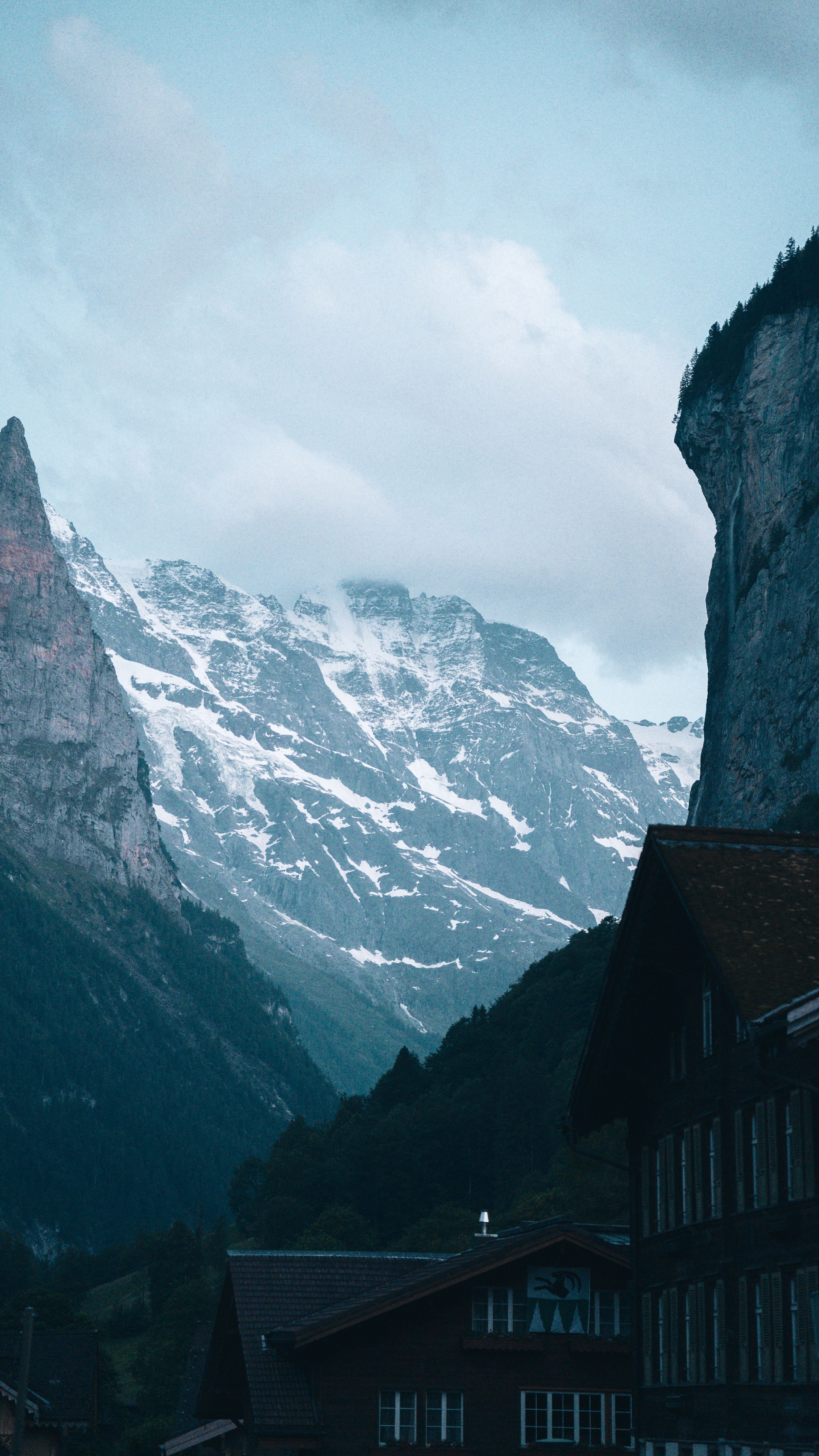 Scenic view of snowcapped mountains and a tranquil mountain village at dusk, exuding a wintery charm.