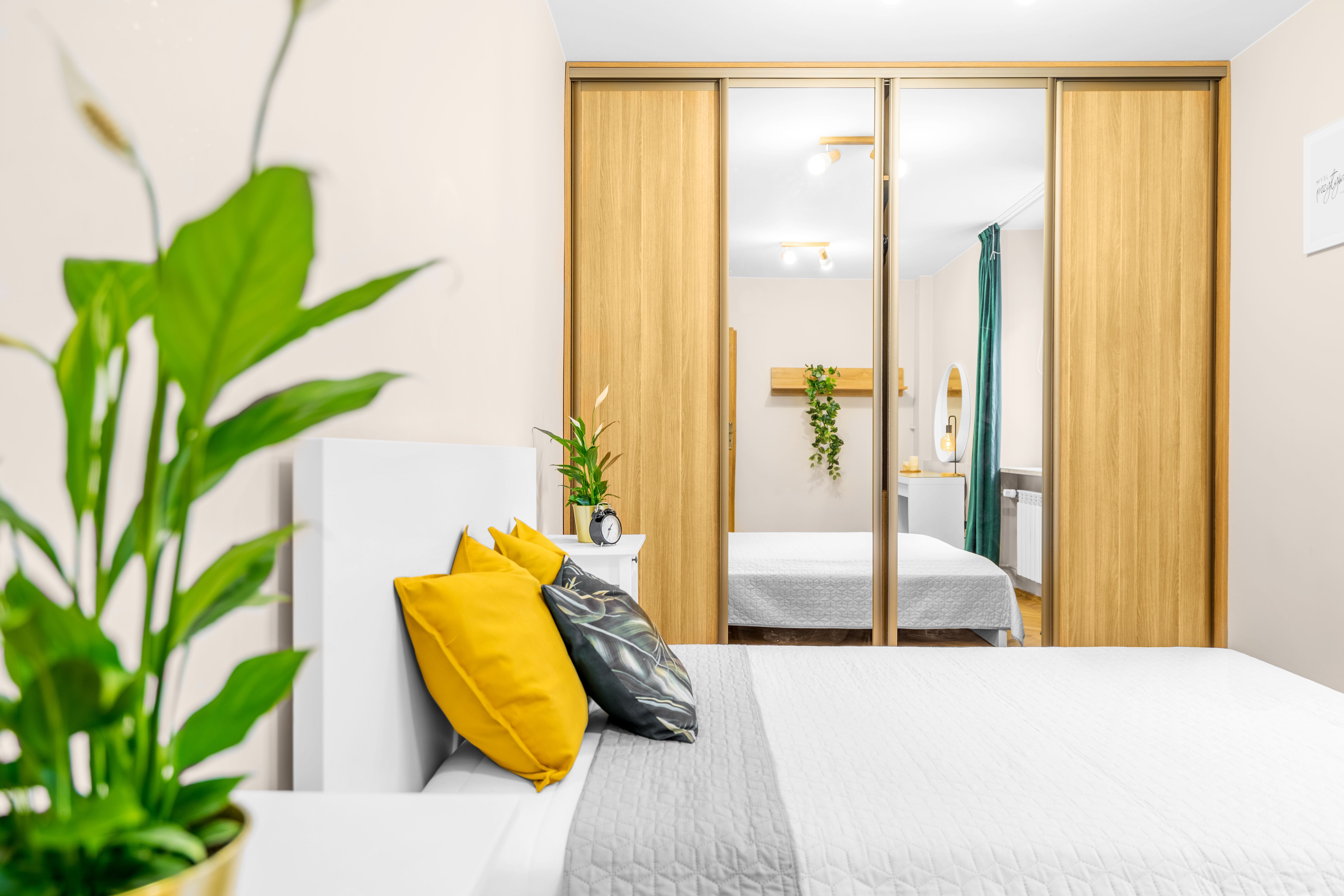 Modern sliding mirror closet doors reflecting a bright contemporary bedroom