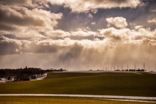 Free Sweeping rural Minnesota fields under a dramatic cloudscape with sun rays piercing through. Stock Photo