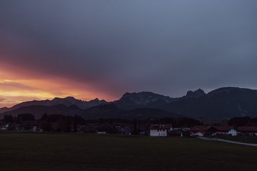 Free Beautiful sunset view over a serene mountain village with colorful sky and silhouette mountains. Stock Photo