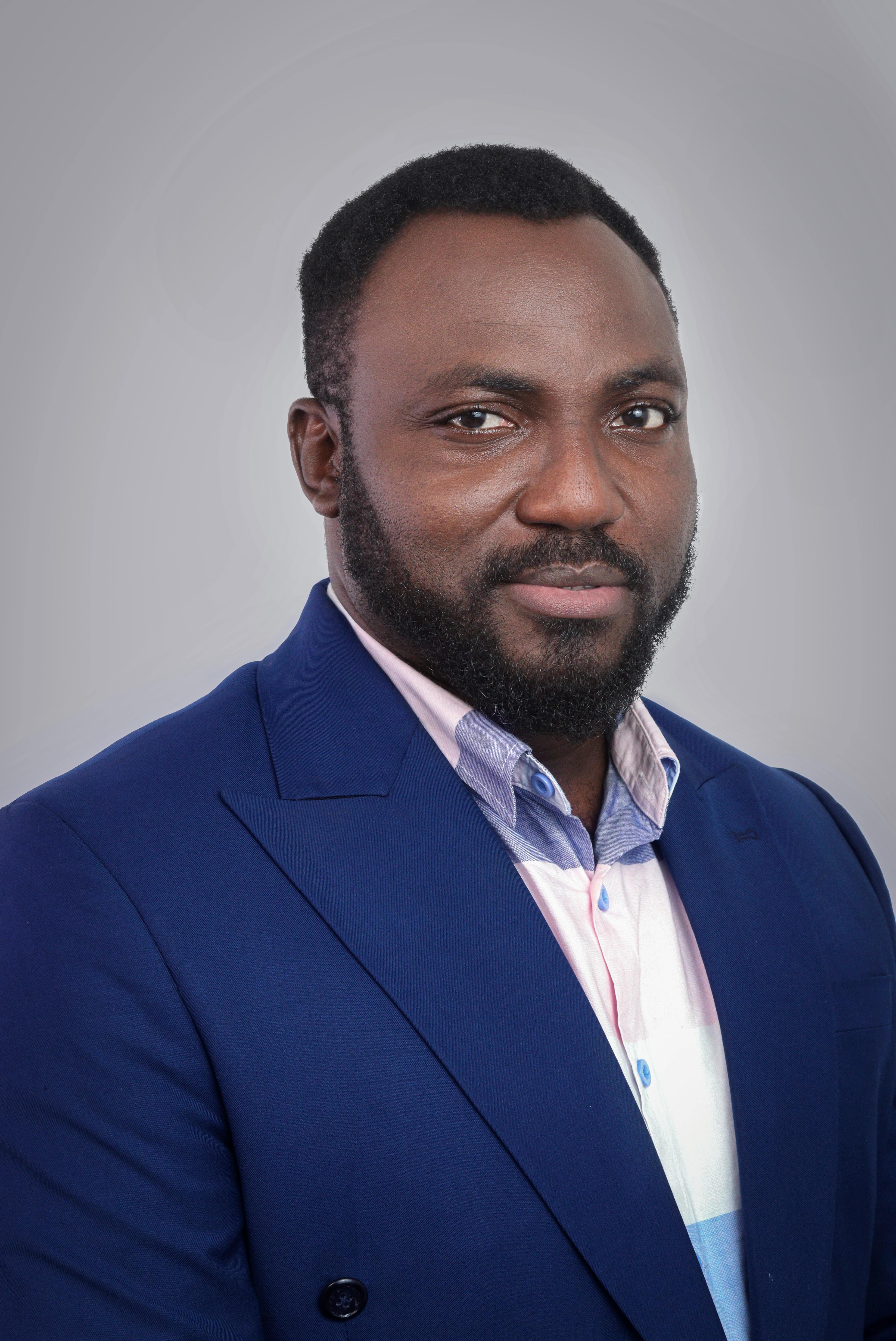 Confident African American man in a blue suit posing against a neutral background.